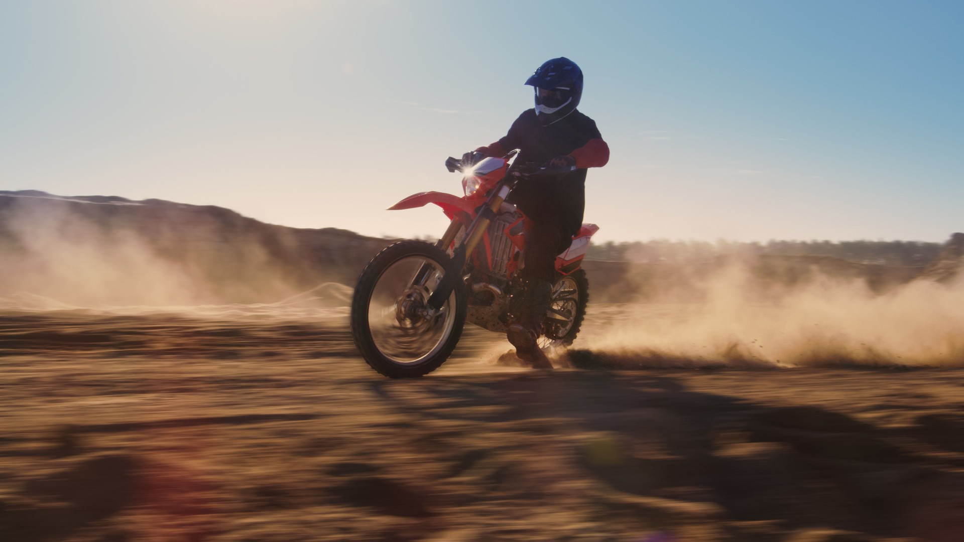 Side View Footage of the Professional Motocross Motorcycle Rider Driving on the Dune. It's Sunset and Track is Covered with Smoke/ Dust/ Dirt. Blur motion.