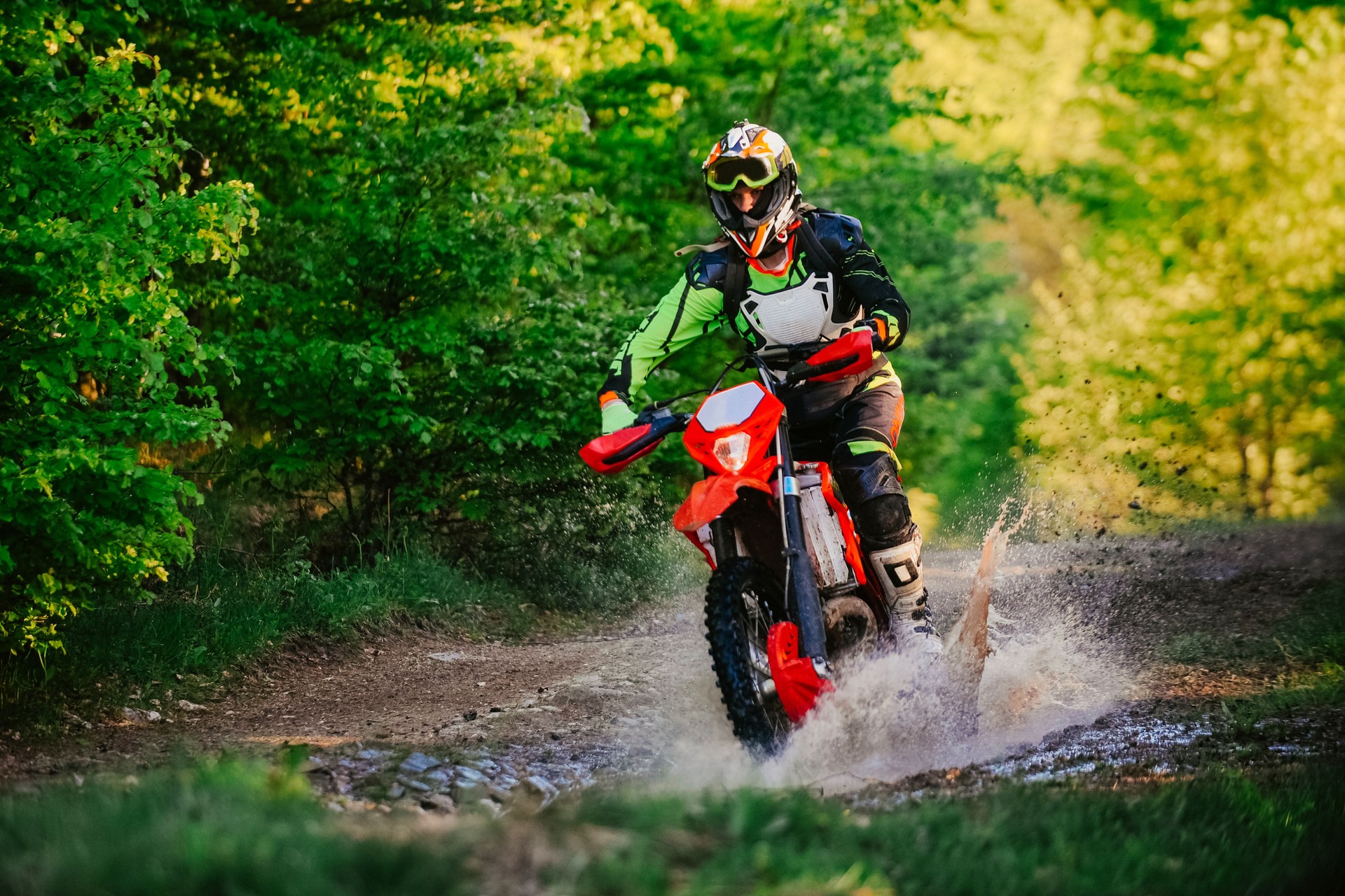 Professional enduro bike rider on action, dirt ride on the muddy road. Motocross sport.